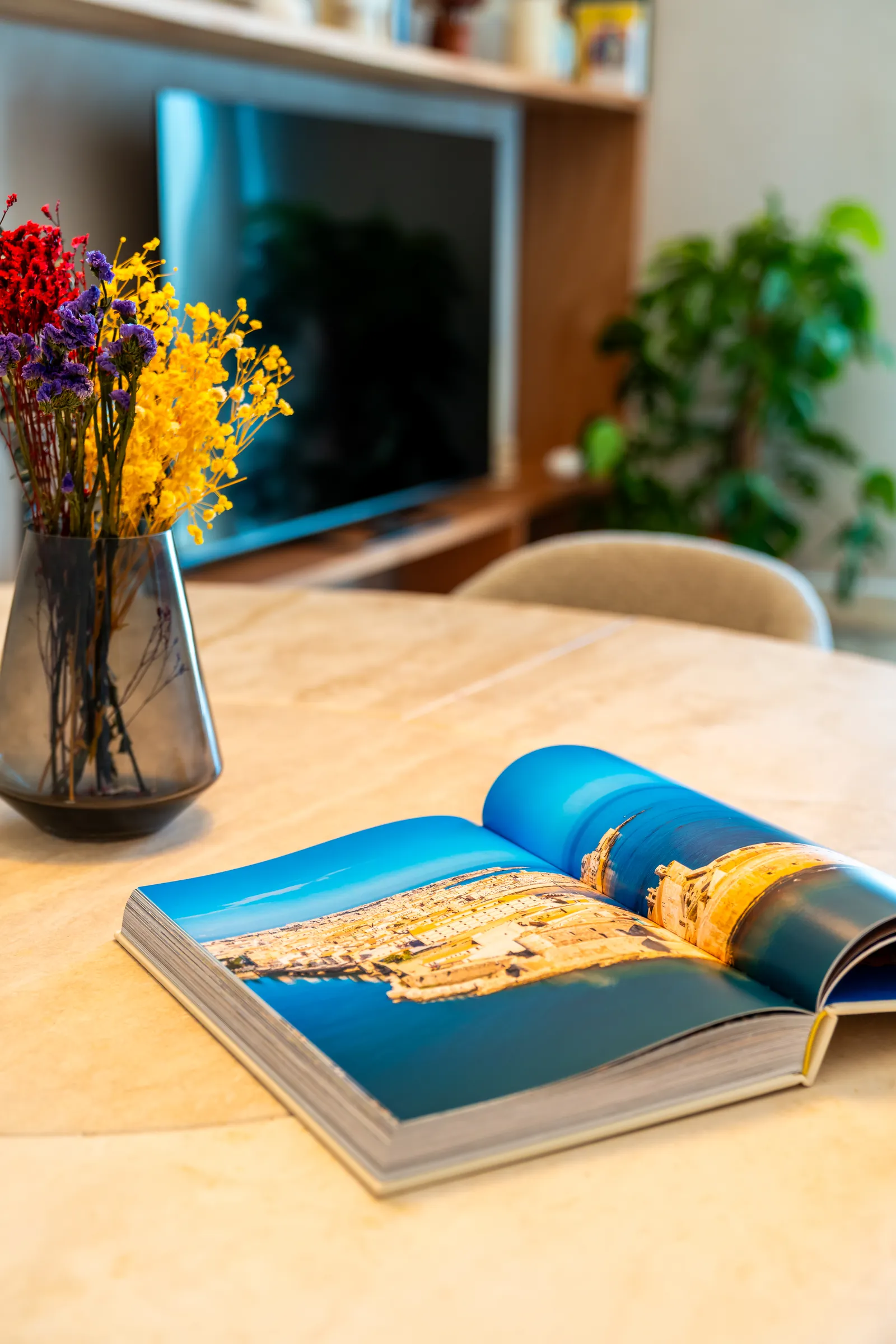 Fiori in un vaso di vetro e un libro sulla Sicilia aperto sul tavolo