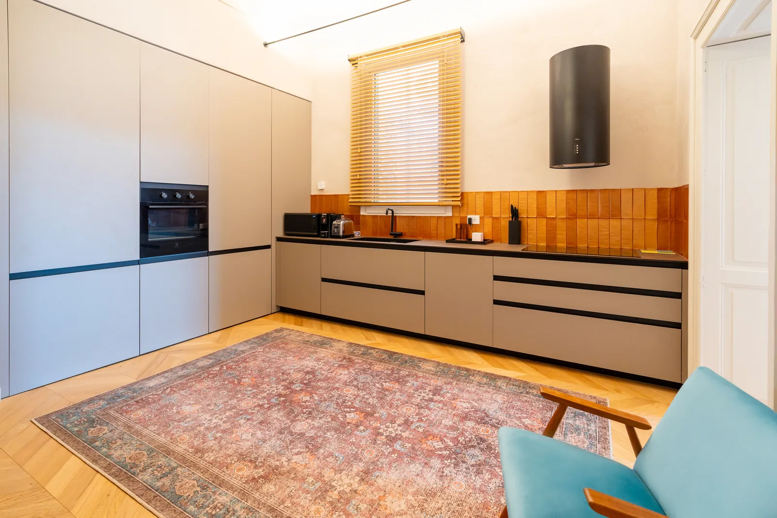 Cucina vista di fronte, con forno a colonna, piano nero e cappa nera