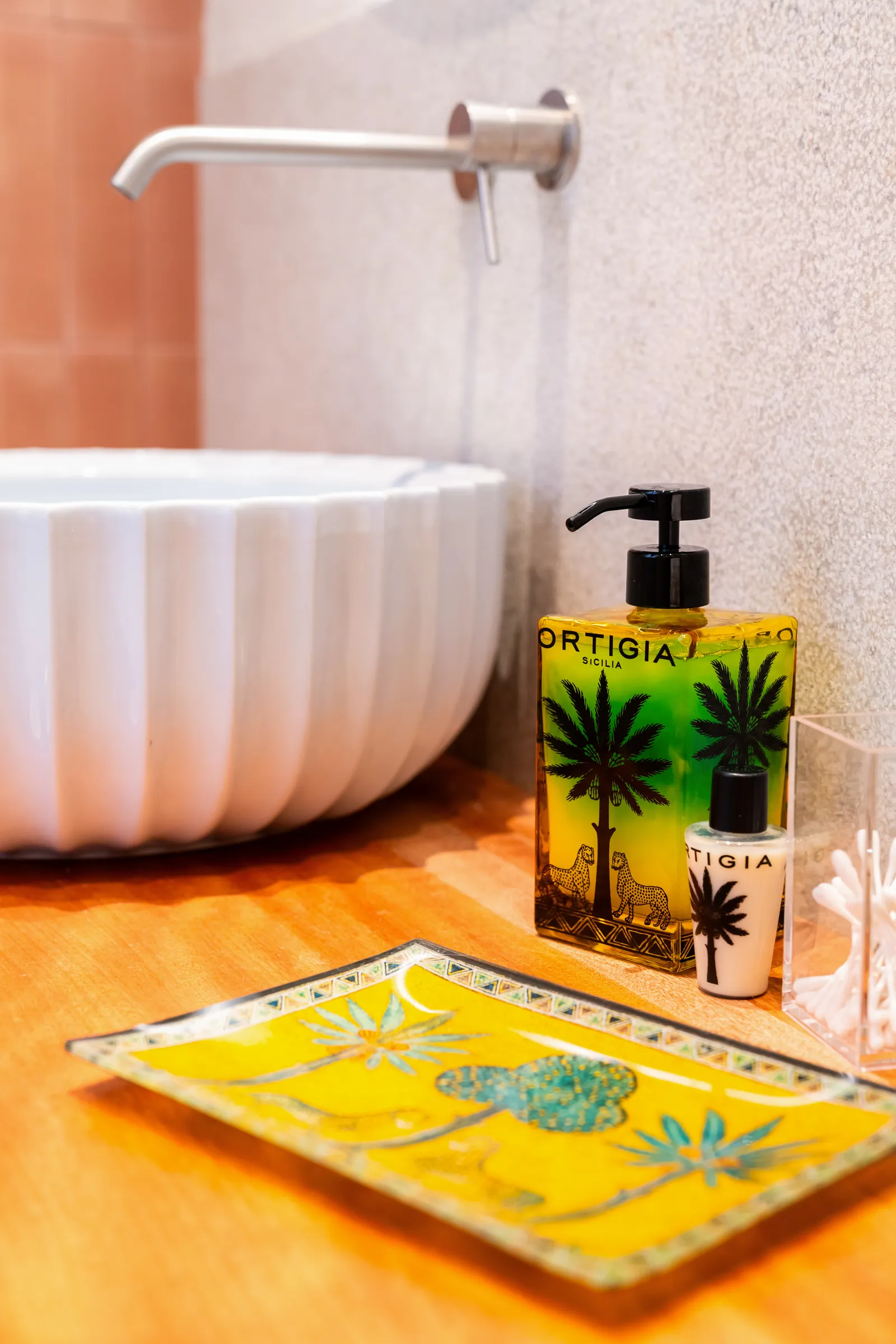 Lavabo a coppa in ceramica bianca, rubinetto a parete e prodotti da bagno Ortigia